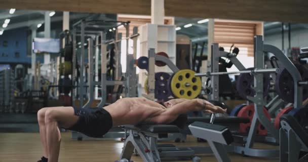 Un jeune homme charmant avec une barbe et il est très tonique, il soulève un poids sur sa tête et travaille sur ses biceps inférieurs 