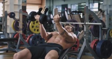 Bir adam onun gübre çan ağırlıkları ile ağır egzersiz yapıyor o çok yakışıklı görünüyor ve onun abs egzersiz konsantre