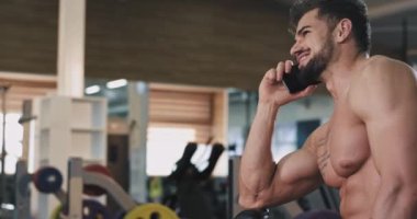 Onun egzersiz egzersizleri arasında bir jimnastik sınıfında fit bir vücut ile Karizmatik adam güzel gülümseyerek telefonunda bir konuşma var