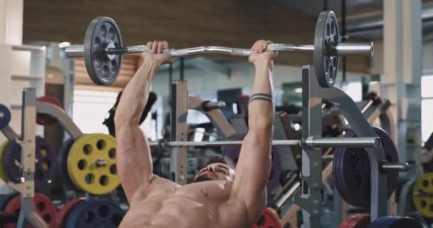 Culturismo chico joven haciendo un entrenamiento en el gimnasio levantando los pesos muy concentrado que trabaja duro — Vídeo de stock