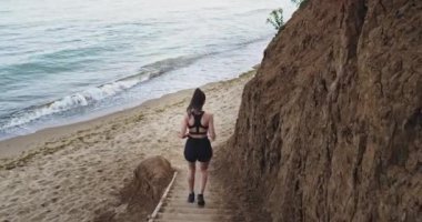 Kahverengi saçlı güzel ve fit kız çok doğal görünüyor bir plaj üzerine, adımlar bir çift aşağı çalışır