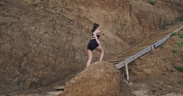 Uma jovem atlética fina sobe alguns degraus, enquanto o ângulo da câmera mostra a paisagem da montanha e vegetação. 4k — Vídeo de Stock
