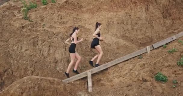 Two young beautiful ladies do some sport and jog up the stairs, in the nature — Stock Video