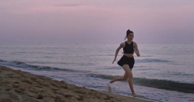 Güzel bayan sabah temiz hava zevk bir spor elbise içinde su ile sahilde çalışan