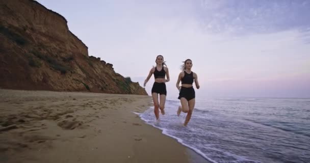 Aantrekkelijke dames hardlopen in de ochtend op het strand met een prachtig uitzicht op de achtergrond — Stockvideo