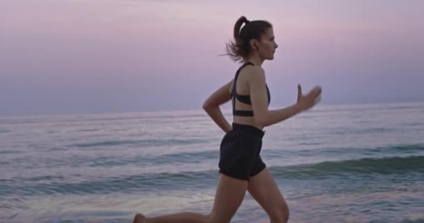 Primer plano señora con el pelo largo corriendo concentrado en el lado de la playa sensación fresca y saludable — Vídeos de Stock