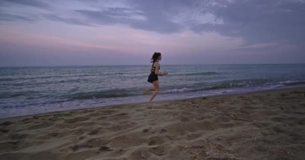 Na praia boa senhora olhando que corre concentrada através do lado do mar na parte da manhã tem um estilo de vida saudável — Vídeo de Stock