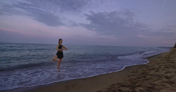 Senhora concentrada praticando ioga no meio da praia tomar as poses de meditação de pé e desfrutar do momento — Vídeo de Stock