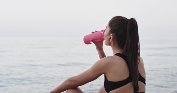 После тяжелой тренировки красивая леди пьет воду и медитации время утром — стоковое видео