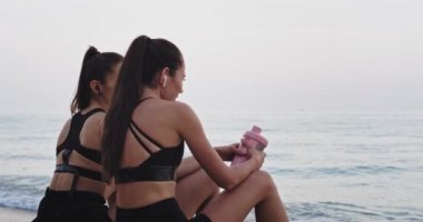 Siyah spor giyim iyi görünümlü bayanlar deniz önünde rahatlatıcı sabah egzersiz sonrası bir mola zaman var birbirleriyle güzel bir konuşma var. yavaş hareketler