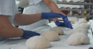 Ticari bir fırın sektöründe çalışan profesyonel fırıncılar ekmek pişirme için hamurparçaları oluşturan