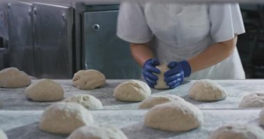 Fırın sektöründe profesyonel işçiler hamur alarak ve fırın makinesinde ekmek pişirme için hazırlanıyor