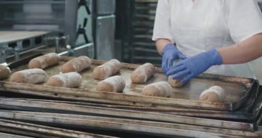 Fırında bir fırın ekmeği için fırın tabağına ham hamur transferi hazırlayan iki profesyonel fırıncılar, gıda sanayi fabrikası