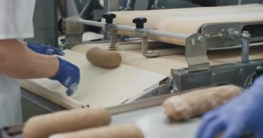 Fırın otomatik konveyör işçileri büyük bir fırın sektöründe raflarda ekmek pişirme hamur hazırlama çiğ ekmek taşıdı