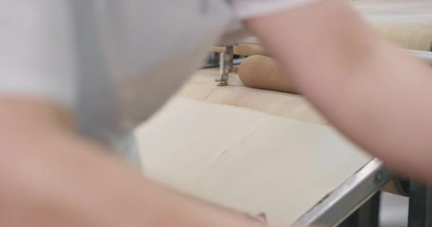 Prozess der automatisierten Förderlinie, die den Teig für das Backen der Brote vorbereitet, die Mitarbeiter der Bäckerei nehmen das rohe Brot und laden es in das Blech — Stockvideo