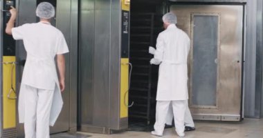 Özel üniformalı fırın endüstrisi profesyonel işçiler ekmek pişirme almak için endüstriyel fırın makinesinde yetiştirilen raflar yük