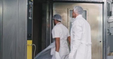 Fırın mühendisi ve beyaz üniforma onun yardımı fırın makinesi üzerinde ekmek yük , mühendis pişirme için özel sıcaklık tüm süreç asistanı programları izler
