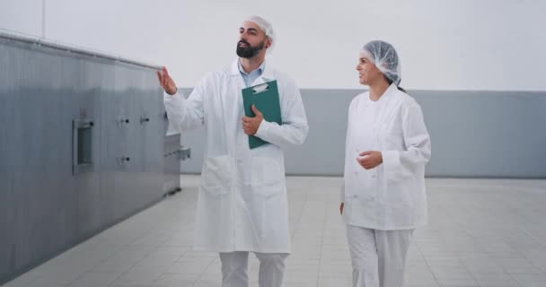 Productie bakkerij industrie Baker en ingenieur wandelen door de fabriek chatten geconcentreerde ingenieur man vasthouden van een kaart — Stockvideo