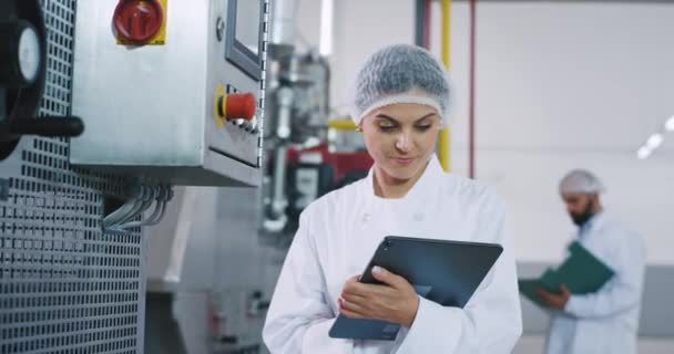 Close up taking video in the manufacturing industry engineer woman good looking take some notes in her electronic tablet and checking the industrial machine — стоковое видео