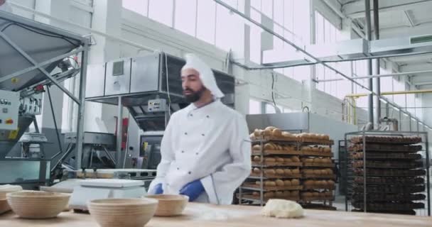 Grote bakkerij-industrie grappige bakker met baard het deeg voorbereiden om brood te bakken en tegelijkertijd te dansen tijdens het luisteren van muziek van draadloze hoofdtelefoons. — Stockvideo