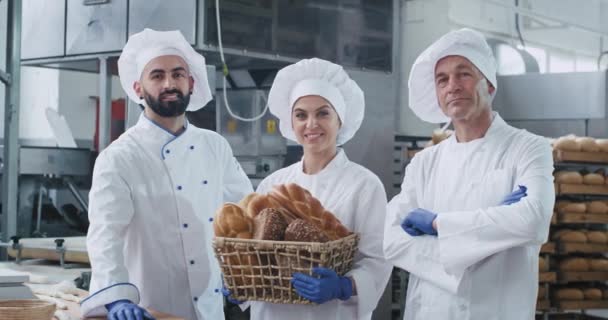 Atractivos hombres panaderos y mujer madura panadero con una cesta vintage con pan orgánico mirando directamente a la cámara y sentirse feliz — Vídeos de Stock