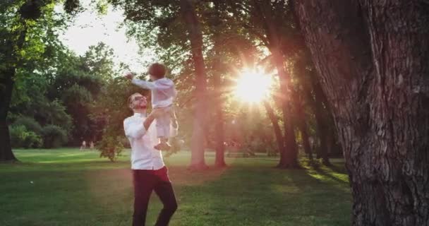 爸爸玩很可爱与他的儿子在公园非常有魅力享受与他的小男孩的时间，他们穿着一个非常时尚的衣服 — 图库视频影像