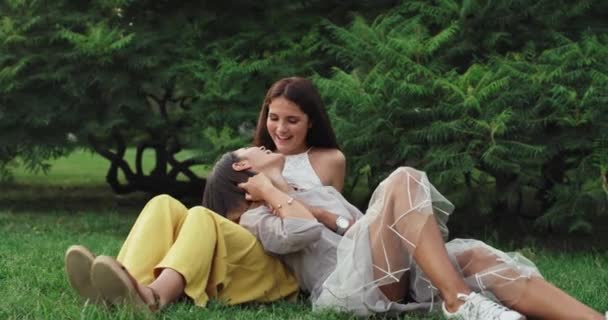 Charyzmatyczny i uśmiechnięty duże dwie ładne Panie spada na trawie korzystających spędzać czas razem w środku parku — Wideo stockowe