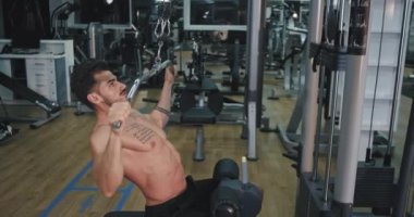 Spor salonunda bir kas vücudu ile iyi görünümlü adam ağırlıkları kaldırarak onun abs geliştirmeye konsantre çalışıyor