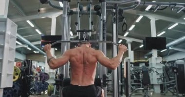Modern jimnastik sınıfı genç vücut geliştirme adam sırtı ve triceps için daha fazla kas almak için ağırlıkları iterek
