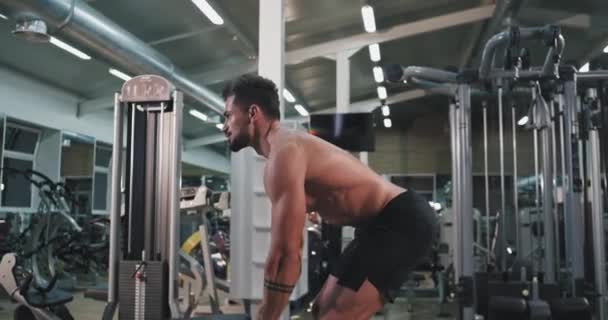 Симпатичный парень с идеальным телом, поднимающий тяжести в спортзале, сосредоточенный, он хорошо работает. — стоковое видео