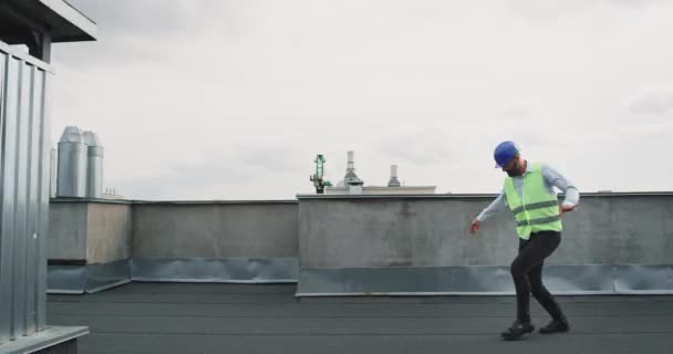 Харизматичный архитектор или инженер на стройке танцует очень взволнованный в защитном шлеме он ходит и двигается очень харизматично — стоковое видео