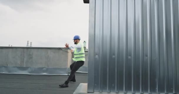 Hombre atractivo con un casco de seguridad en la azotea del ingeniero de obra o arquitecto bailando emocionado en medio de la jornada laboral — Vídeos de Stock