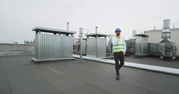 Mladý konstruktér s plnovousem ve tvrdé bezpečnostní helmě tančící na střeše staveniště je velmi šťastný — Stock video