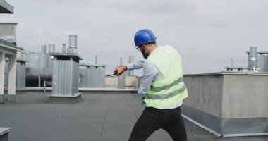 Şantiye nin çatısında komik iyi görünümlü mimar dans ve çok heyecanlı bir güvenlik kask ve iş kıyafetleri giyen duygu