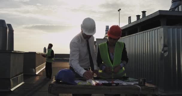 Le vieil homme blanc beau constructeur, pointe vers l'arrière et quatrième à la planche à dessin et le site pour montrer à la femme ouvrière de la construction éblouissante ce qu'il voudrait faire, comme un homme en forme dans un film de barbe avec — Video