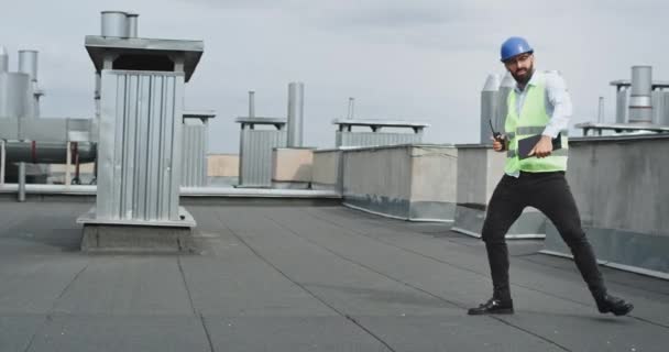 Construção edifício moderno arquiteto ou engenheiro dançando animado enquanto segurando um tablet e ração vestindo um capacete de segurança — Vídeo de Stock