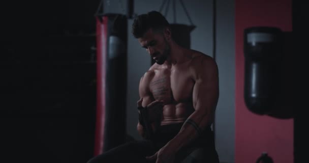 Young charismatic athletic man preparing for training in the gym class he wraps his hands using the professional bandages — Stock Video