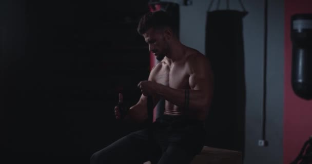 Bodybuilding man preparing for the training in a gym class wraps the hands with a elastic professional bandages get ready to start the workout — Stock Video