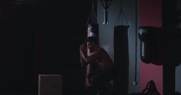 Perfect uitziende kerel met een spier lichaam het doen van een harde workout oefeningen in een cross fitness-klasse hij springen op de houten kisten hebben een intensieve training — Stockvideo