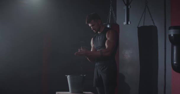 Great looking fit guy concentrated get some powder on his hands preparing to start the workout he have full sportswear for a cross fit exercises — Stock Video