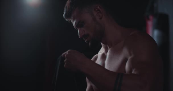 Attraktiver Kerl konzentriert mit einem professionellen Verband wickelt seine Hände und bereitet sich auf sein Training im Fitnessstudio vor — Stockvideo