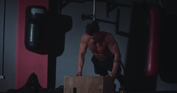 Joven con un cuerpo perfecto en una clase de fitness haciendo flexiones sobre la caja de madera concentrado se pone dulce — Vídeos de Stock