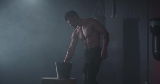 Konzentrierter Bodybuilding-Mann nimmt etwas Puder auf seine Hände und bereitet sich auf einen intensiven Trainingstag in einem Cross-Fitness-Kurs vor — Stockvideo