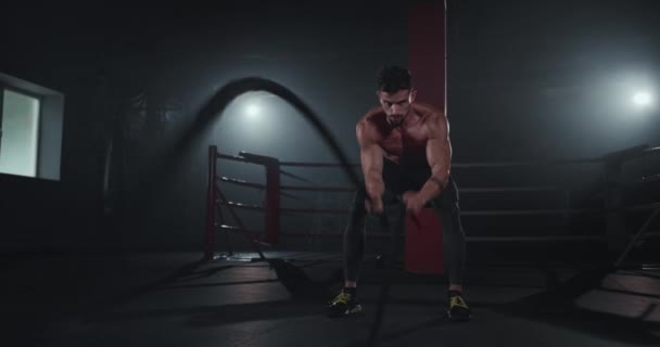 Attrayant gars musculation dans un cours de remise en forme croisée en utilisant des cordes concentrées faire son entraînement — Video