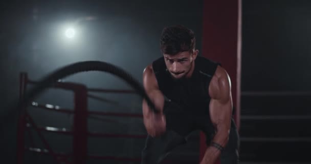 Atraktivní mladý muž má tvrdé cvičení ve třídě pro cross fitness a používá lana, se kterými pracuje. — Stock video