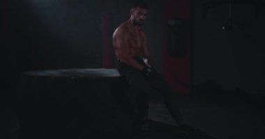 Brutal dize uygun vücut adam onun sert egzersiz eğitimi kamera yorgun ve çapraz fitness sınıfında terleme bakarak lastik oturan sonra