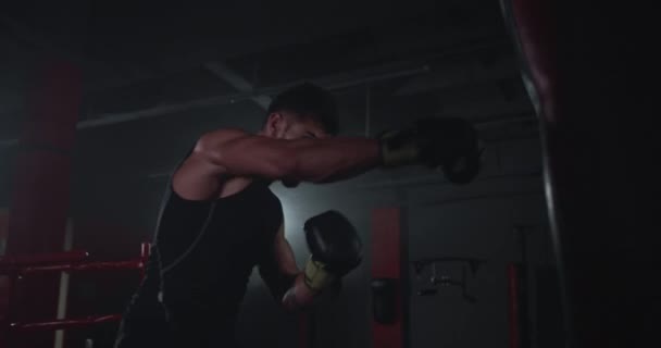CrossFit concept athletic brutal guy boxing hard into the punching bag , practicing hard sport workout — Stock Video