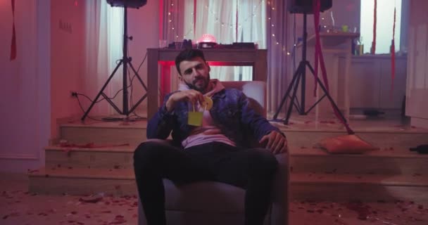 Vážně, muž na domácí párty si užívá odpočinku a cítí se uvolněně, když pije koktejl, spoustu dekorací. — Stock video