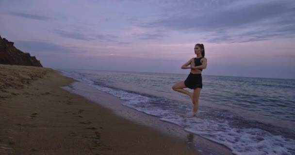 Deniz kenarındaki Yoga zamanı. Plajdaki bayan meditasyon yapıyor. Sabahları temiz hava alıyor. — Stok video