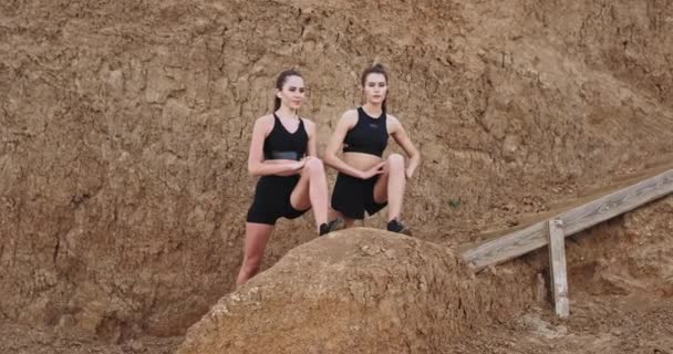 Sportliche Frauen machen morgens ein hartes Workout, strecken die Beine draußen neben den Holztreppen und hören Musik aus drahtlosen Kopfhörern. — Stockvideo